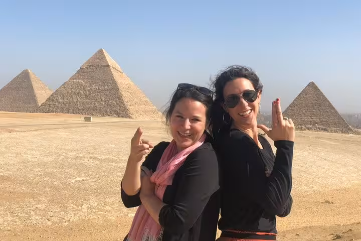 Travelers posing at the Giza Pyramids plateau during a private guided tour with panoramic desert views, Cairo