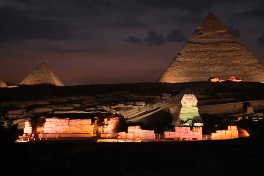 Sphinx and Great Pyramid illuminated during Giza sound and light show tour, night view of Cairo desert plateau