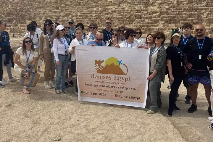 Tour group at the Giza Pyramids posing by the stone blocks during a private Pyramids and Sphinx day tour