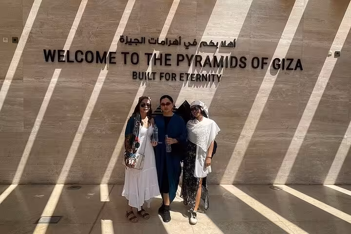 Guests posing at Welcome to the Pyramids of Giza sign on a private Giza pyramids and Sphinx day tour