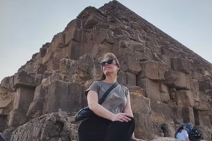 Traveler seated by ancient stone blocks at Giza Pyramids on Cairo Airport private trip to Egyptian Museum and Coptic Cairo