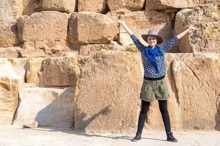 Visitor posing by massive limestone blocks at Giza Pyramids complex, skip-the-line entry ticket and site access