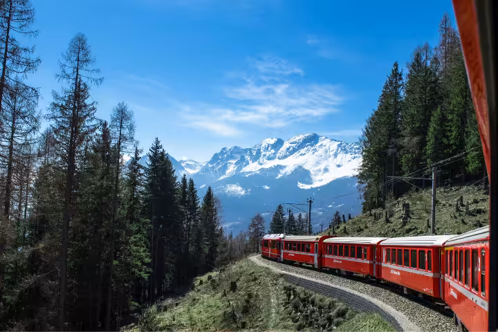 Glacier Express red train on scenic Swiss Alps curve, premium Zurich route tour with mountain views