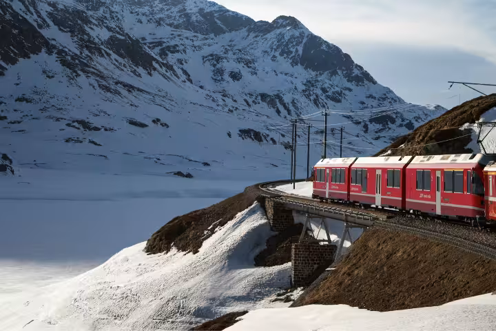 Glacier Express train on a snowy Swiss Alps curve, scenic private tour route from Zurich to Zermatt