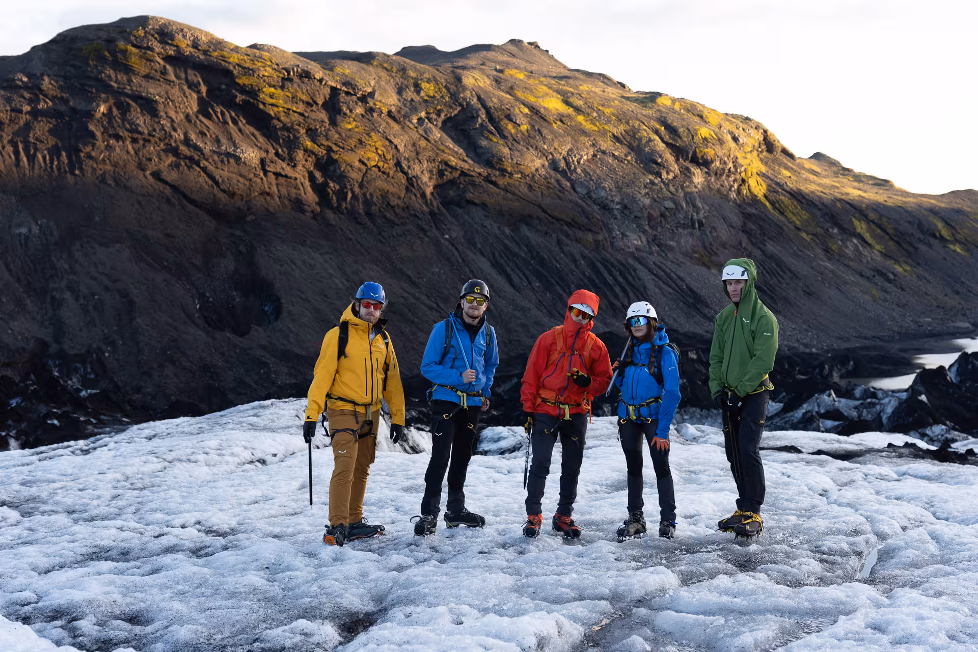 Group in helmets and crampons posing on Sólheimajökull glacier during guided Iceland glacier hike tour