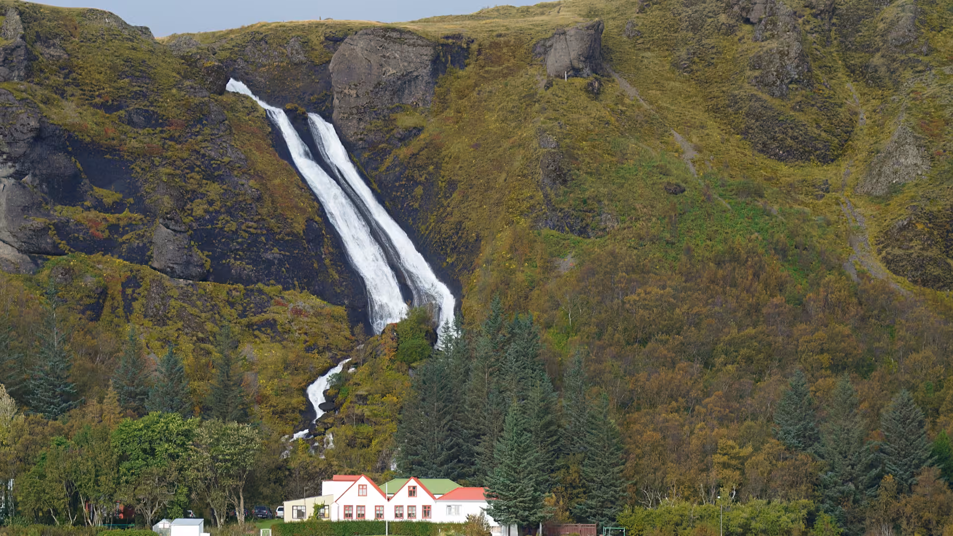 Twin waterfall over green Icelandic hills on Glacier Lagoon private rally car tour, South Coast photo stop