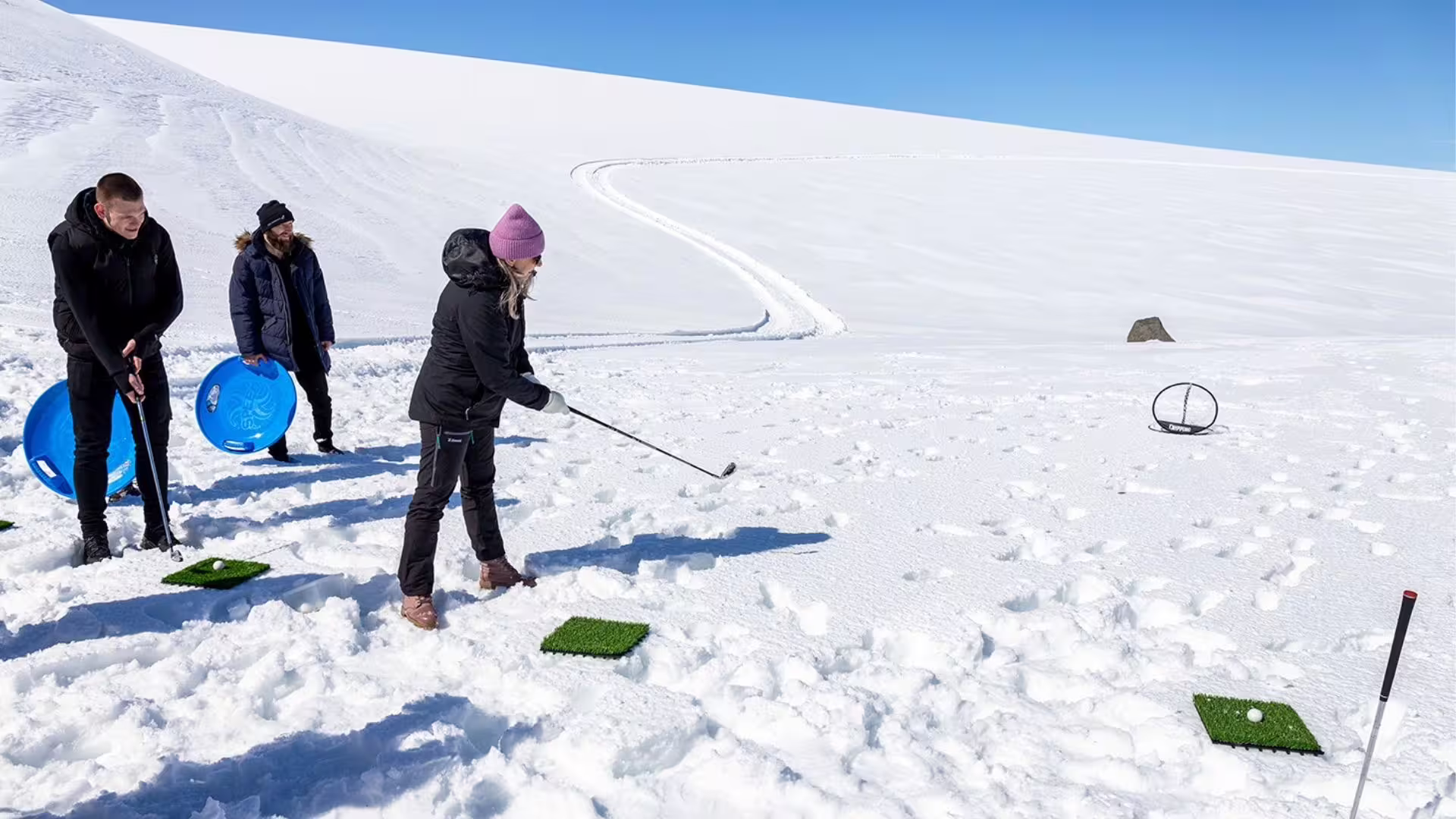 person playing golf ontop the glacier, standing in white snow