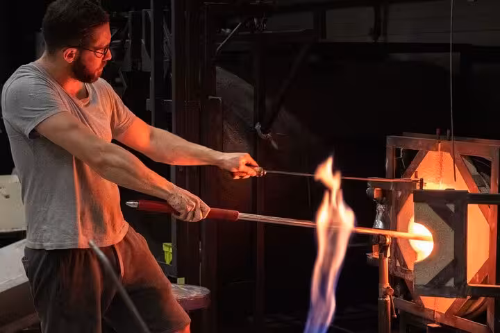 Skilled artisan shaping glass with fire at a perfume factory on a private tour showcasing glassblowing craftsmanship.
