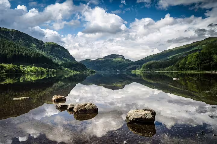 Mirror-still Highland loch with rocky shore and mountain reflections, Glencoe and Highlands Adventure day trip