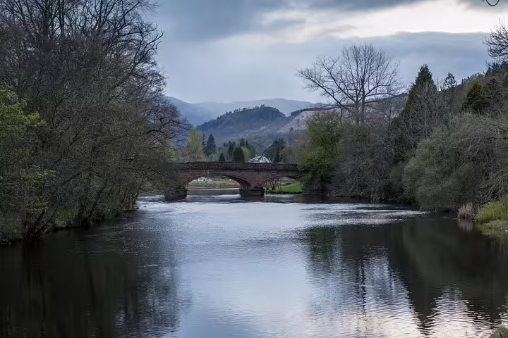 Stone bridge over calm Highland river with distant hills, tranquil view on Glencoe and Highlands Adventure tour