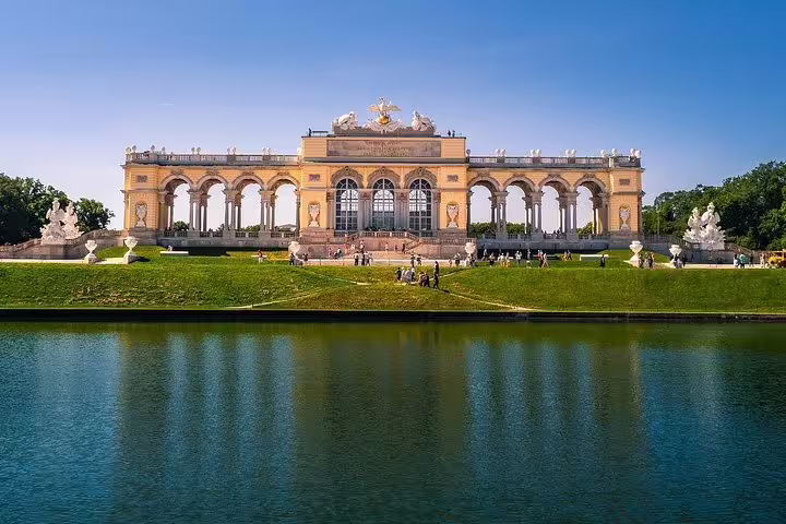 Historic Gloriette in Vienna's Schönbrunn Palace gardens, a highlight of private half-day sightseeing tours, reflecting in serene pond.