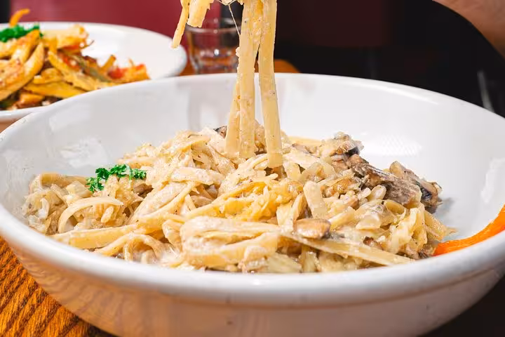 Indulge in gluten-free fettuccine Alfredo with mushrooms from Chef Christian's Roman culinary experience.
