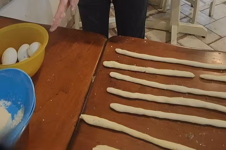 Hands preparing gluten-free pasta dough strips on a wooden table for a cooking course in Rome.