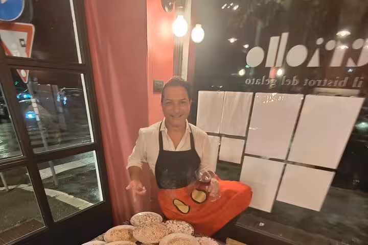 Chef presenting a variety of gluten-free pasta dishes with a glass of wine at a cozy Roman cooking class.
