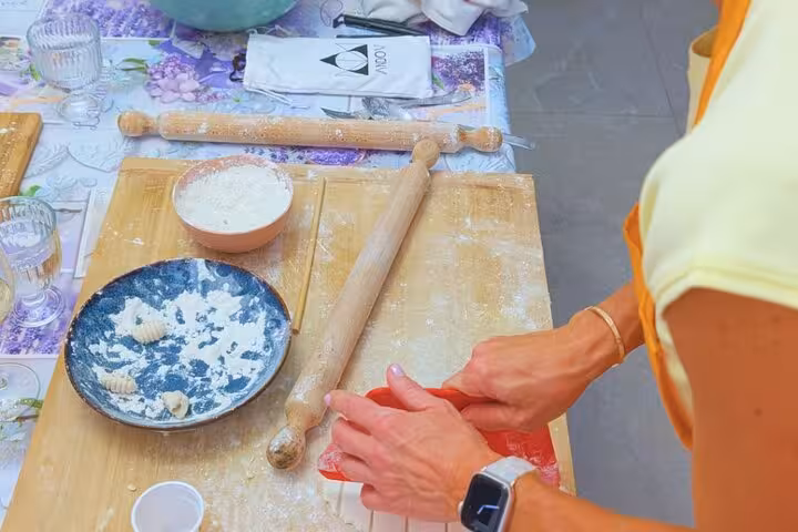 Participant shaping gluten-free pasta on a wooden board during Chef Christian's Roman feast cooking class.
