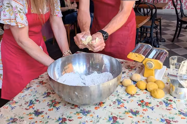 Two people kneading gluten-free dough in a large bowl at a Roman cooking class with Chef Christian.