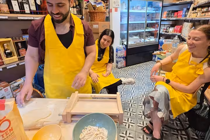 Participants in yellow aprons make gluten-free pasta during the Roman Feast Cooking Class with Chef Christian.
