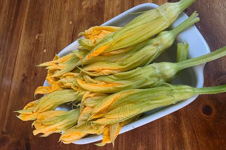 Fresh zucchini flowers in a dish, ready for cooking at a gluten-free Roman feast class with Chef Christian.