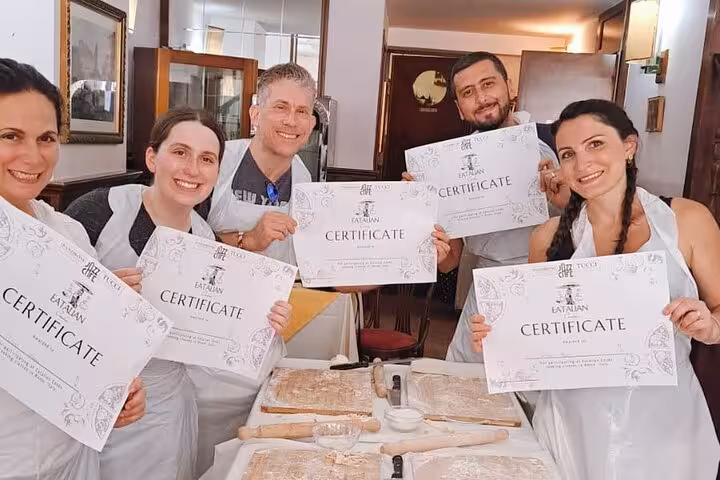 Proud participants display certificates after completing the gnocchi cooking class in Rome.