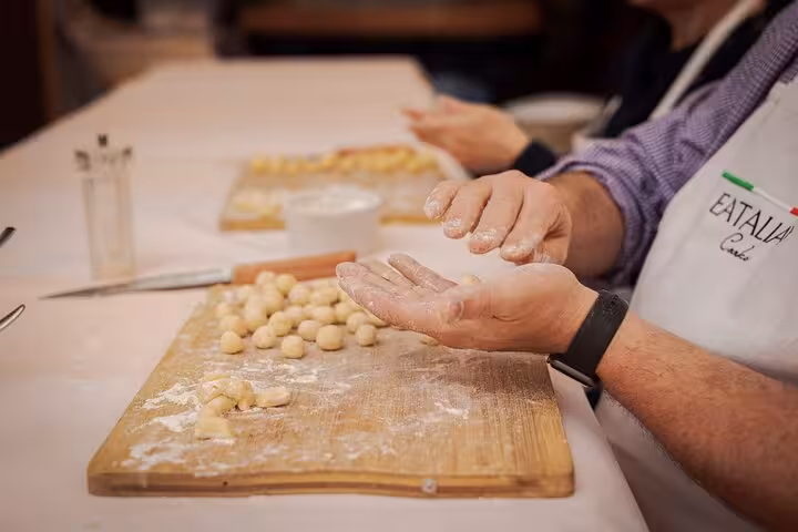 Participants shaping fresh gnocchi by hand on a wooden board during a cooking class near Piazza Navona, Rome.