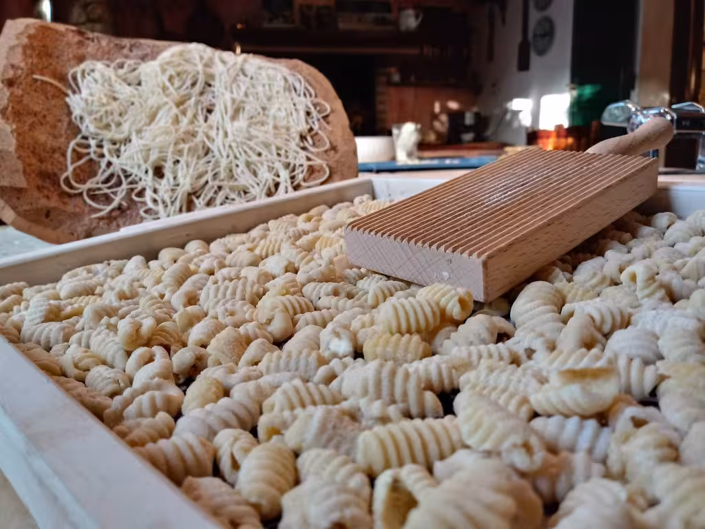 Close-up of freshly made gnocchi and pasta on wooden board during Olmedo cooking class experience.