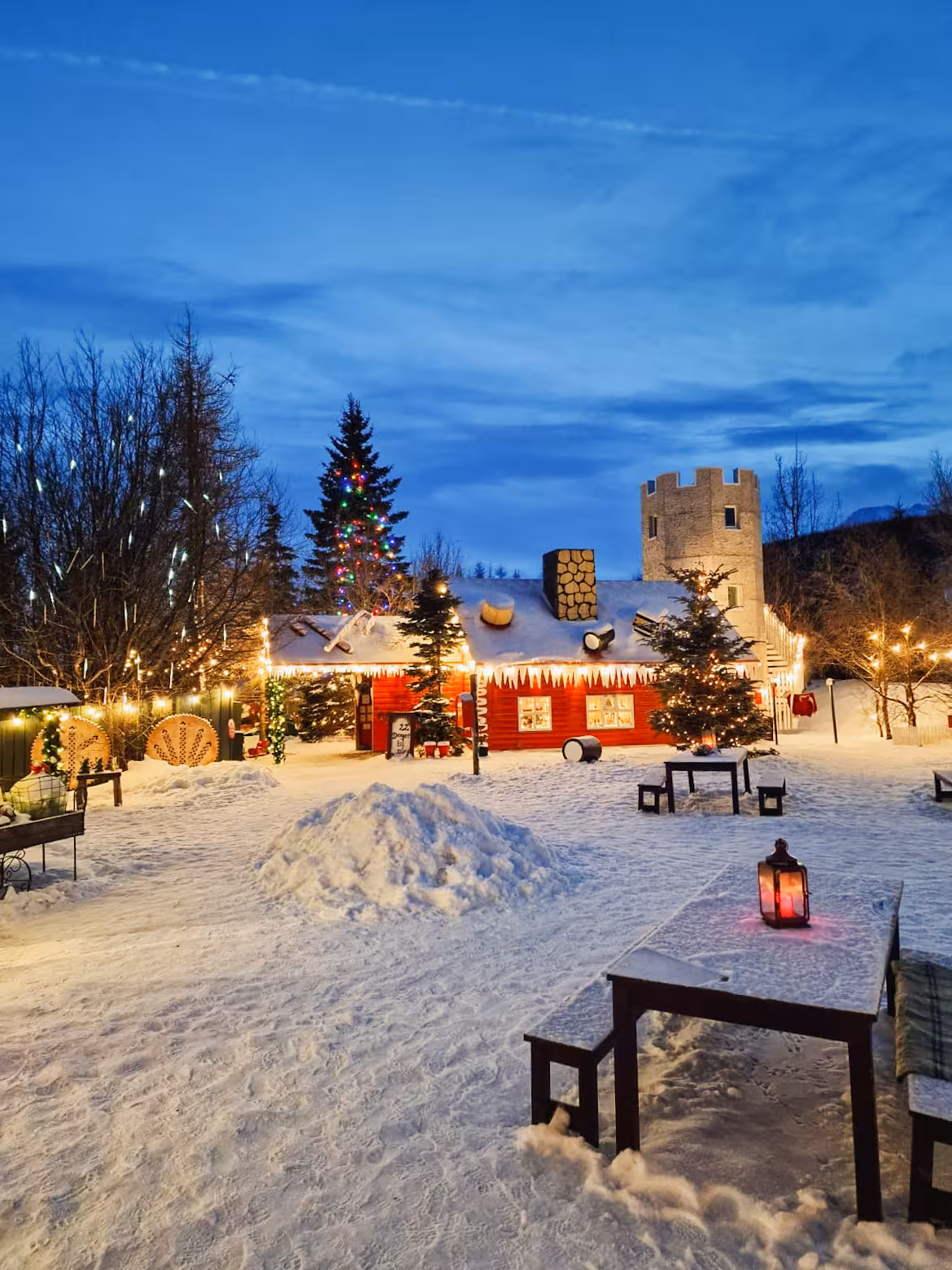 Twilight view of Akureyri Christmas House in snowy garden with lights, part of Goðafoss and Forest Lagoon tour