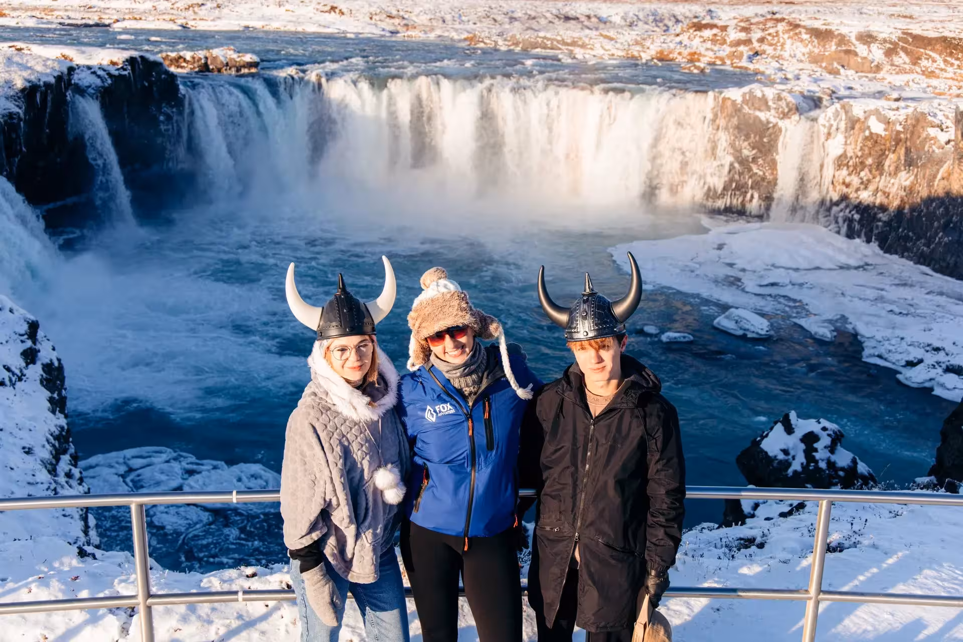 Guests in Viking helmets at Goðafoss Waterfall in winter, private Sacred Iceland tour with Christmas cacao ceremony