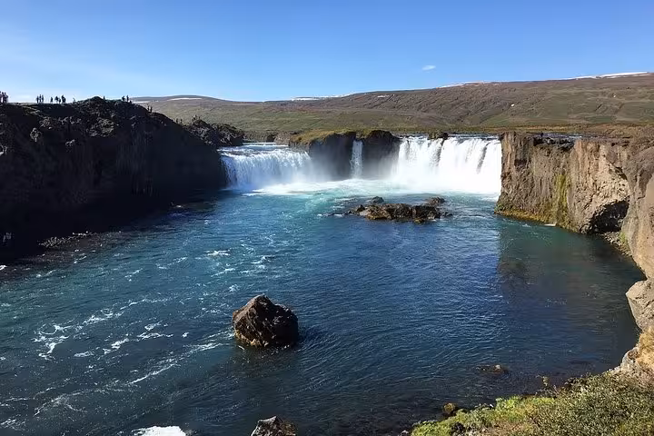 Scenic view of Godafoss Waterfall surrounded by lush greenery on a sunny day during the Lake Myvatn 4x4 tour.