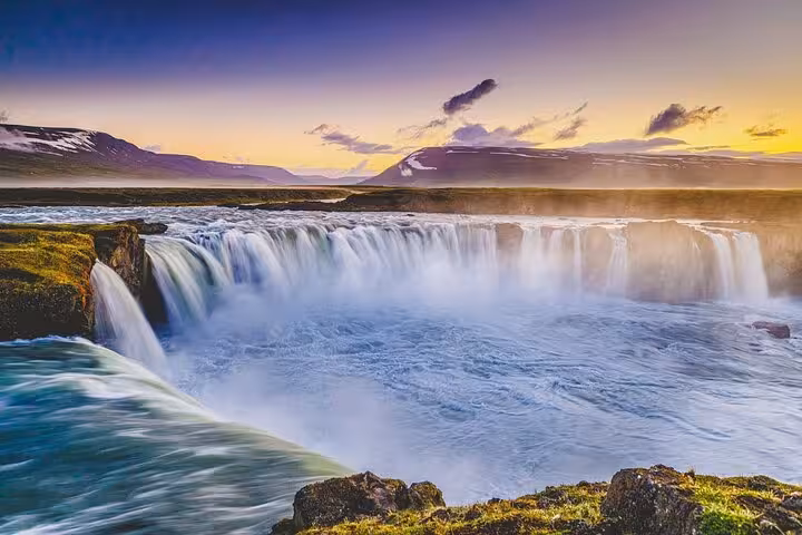 Stunning sunset view of Godafoss waterfall in Iceland with vibrant skies and cascading waters, ideal for Akureyri tours.