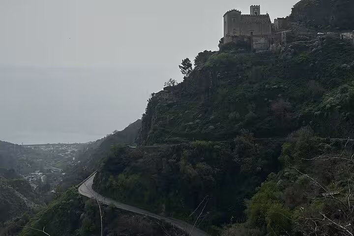 Scenic view of a historic castle perched on a lush hilltop with a winding road, perfect for 'The Godfather' tour.