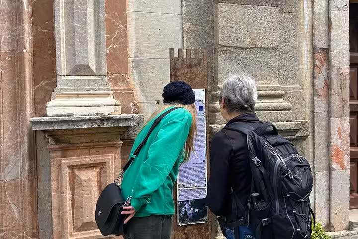 Visitors explore historic sites on a guided Godfather tour, examining detailed information outside an old stone building.