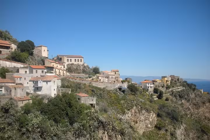 Scenic view of Savoca village with rustic buildings perched on a cliff under a clear blue sky, featured in The Godfather tour.