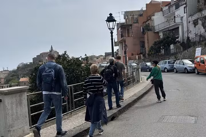 Tour group strolls through picturesque Sicilian town, retracing iconic Godfather movie locations and enjoying scenic views.