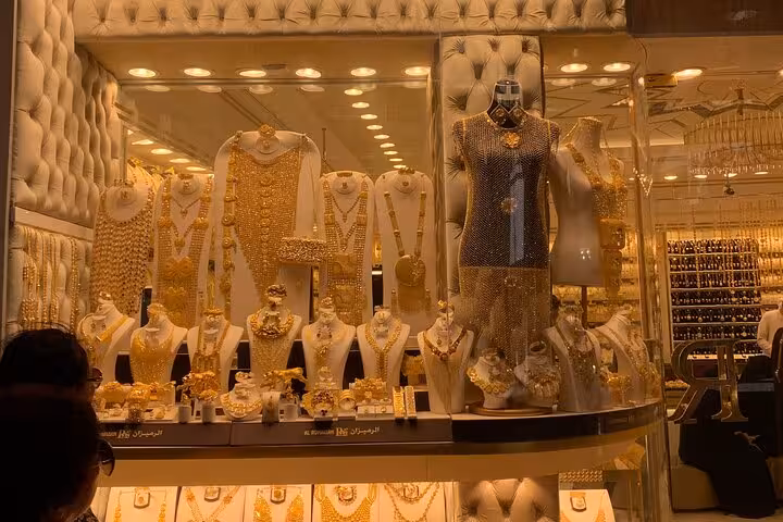 Gold jewelry shop window at Dubai Gold Souk, showcasing ornate necklaces and bridal sets on display