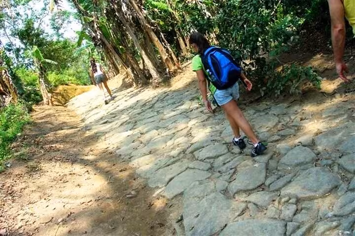 Hikers exploring the lush, cobblestone path of the Gold Trail Adventure, offering a blend of nature and culture.