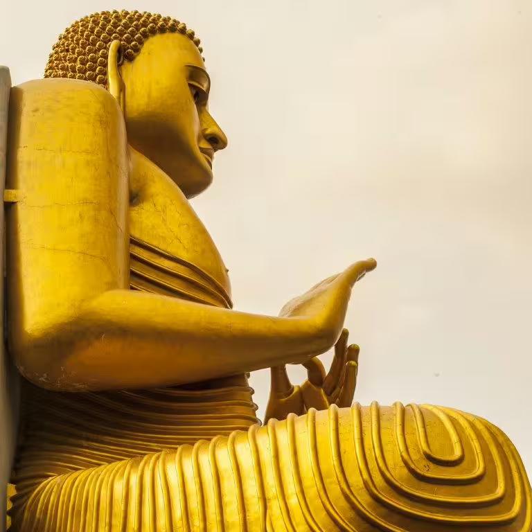 Majestic golden Buddha statue in Sri Lanka showcasing intricate details against a tranquil sky, a must-see cultural landmark.