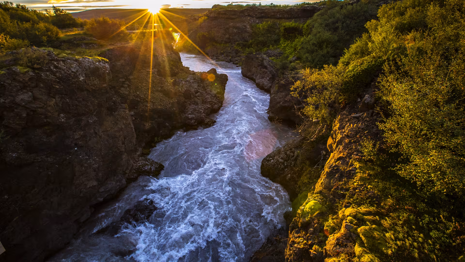 Scenic view of a sunlit canyon with a flowing river in Iceland's Golden Circle Tour.