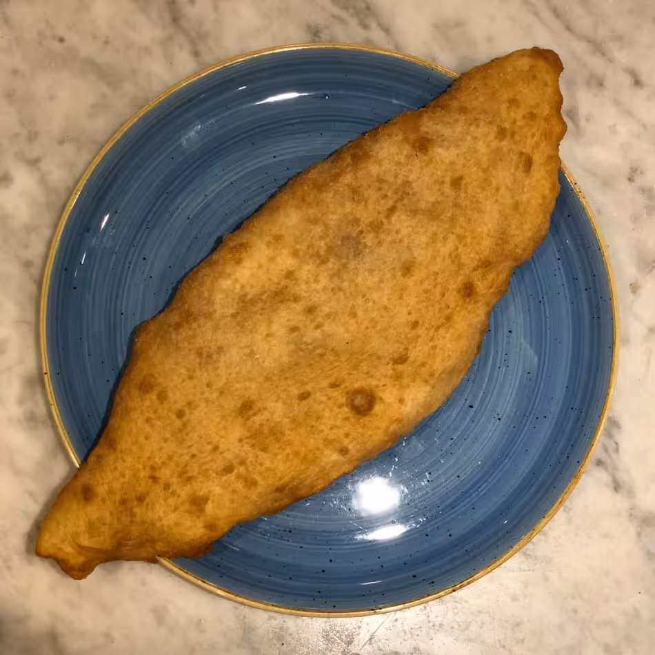 Golden fried pizza calzone on blue plate, classic Neapolitan street food tasting on Naples street food tour