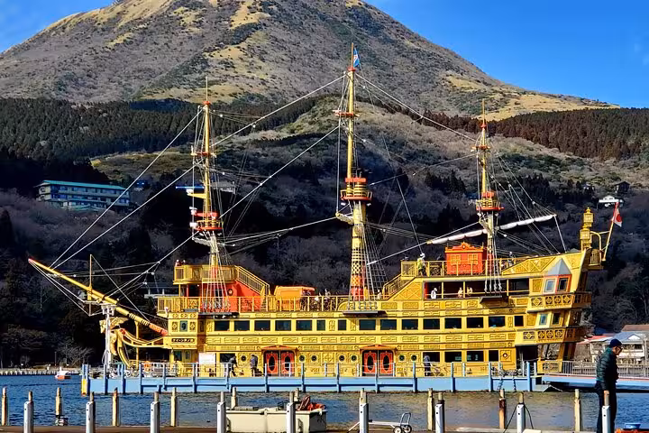 Golden pirate ship on Lake Ashi with Mt. Hakone backdrop, part of English Guided 2 Days Mt. Fuji and Hakone Private Tour.