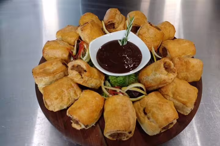 Platter of golden sausage rolls with dipping sauce, a savory delight featured in the 3-hour culinary exploration tour.