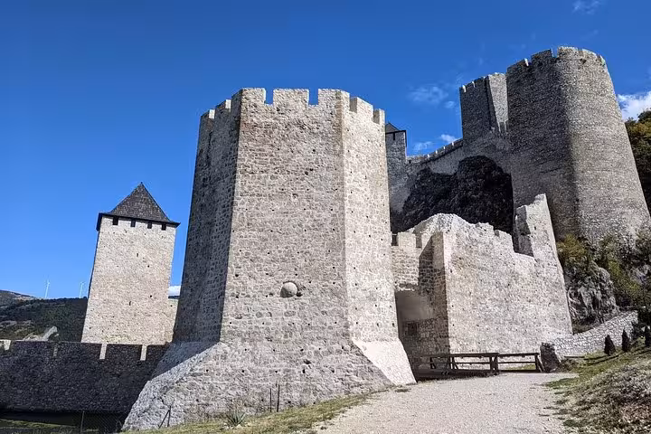 Close-up of Golubac Fortress's stone walls and towers against a clear blue sky, highlighting its historical grandeur.
