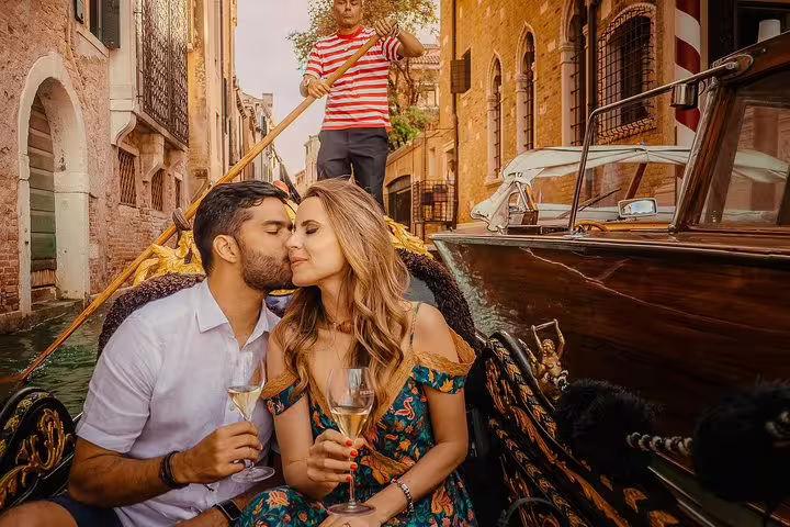 Romantic gondola ride in Venice with a couple enjoying champagne and a serenading gondolier.
