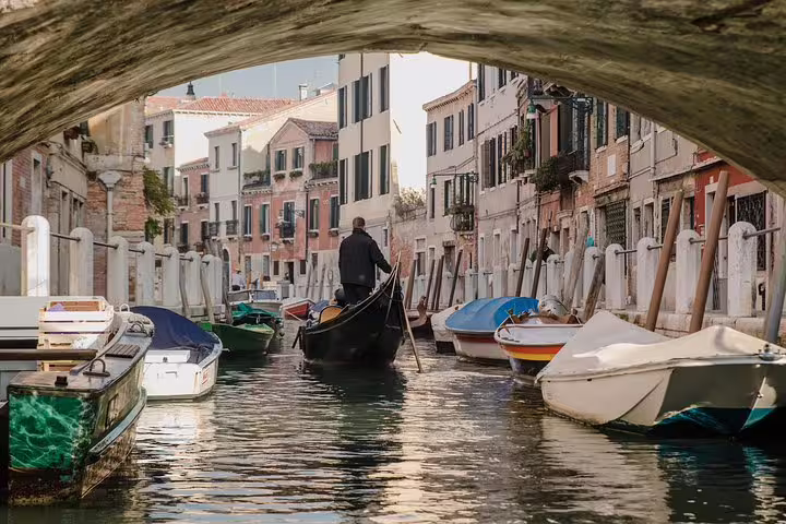 Serene gondola ride through a picturesque Venetian canal, offering a unique view of historic buildings under a bridge.