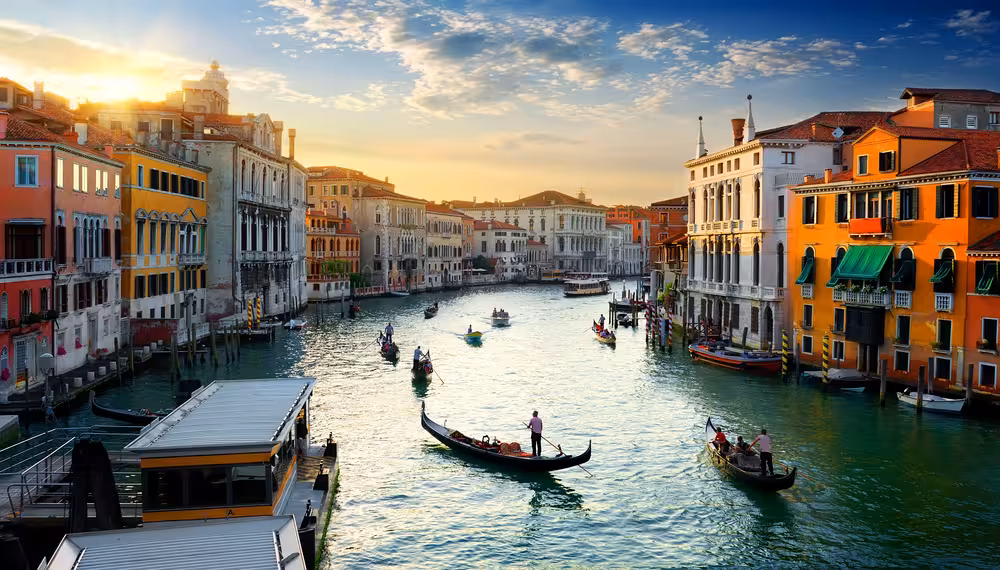 Gondolas gracefully glide along Venice's Grand Canal during a picturesque sunset, showcasing historic architecture.
