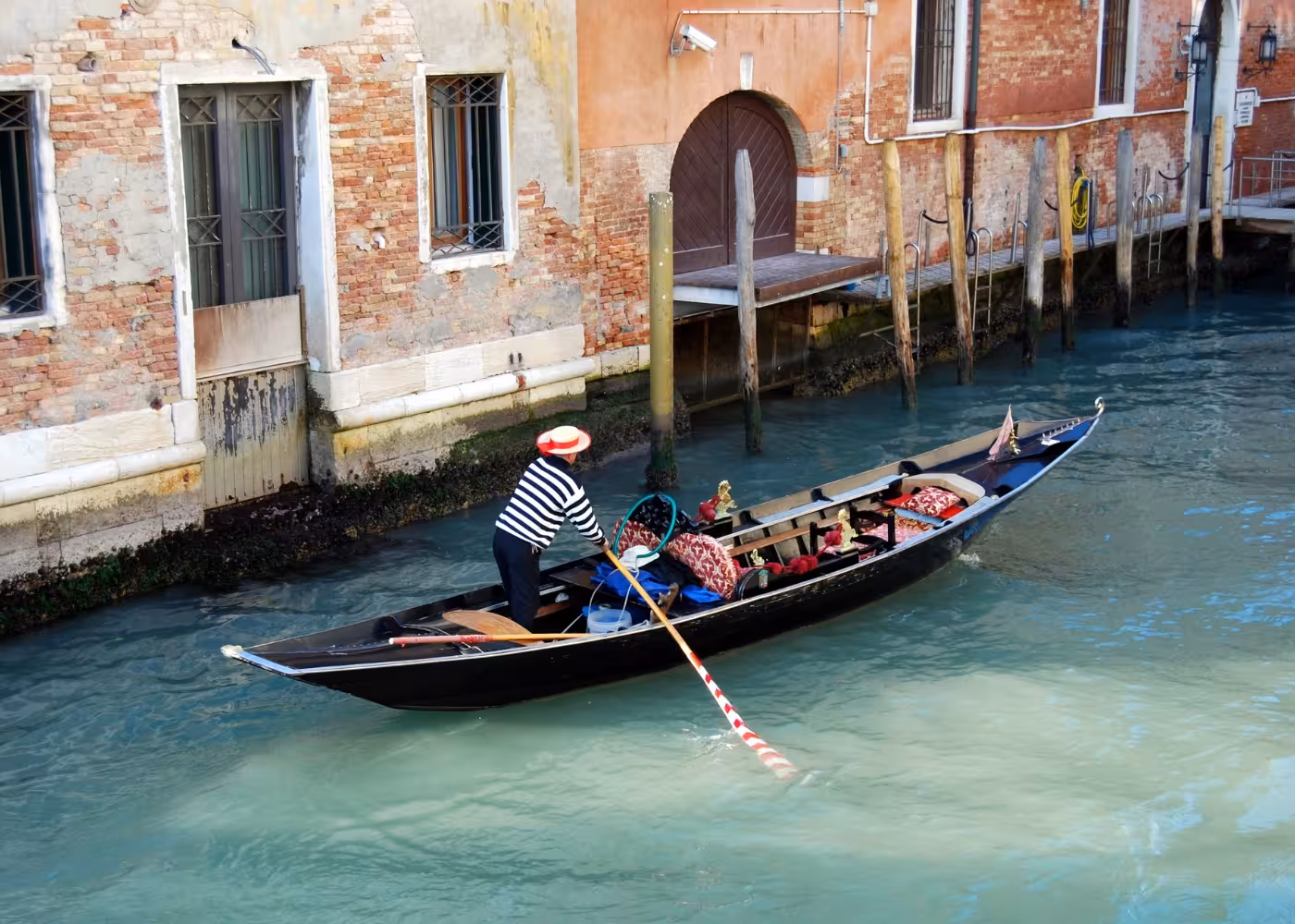 Gondolier navigates charming Grand Canal beside rustic Venetian architecture, perfect for a romantic gondola ride.