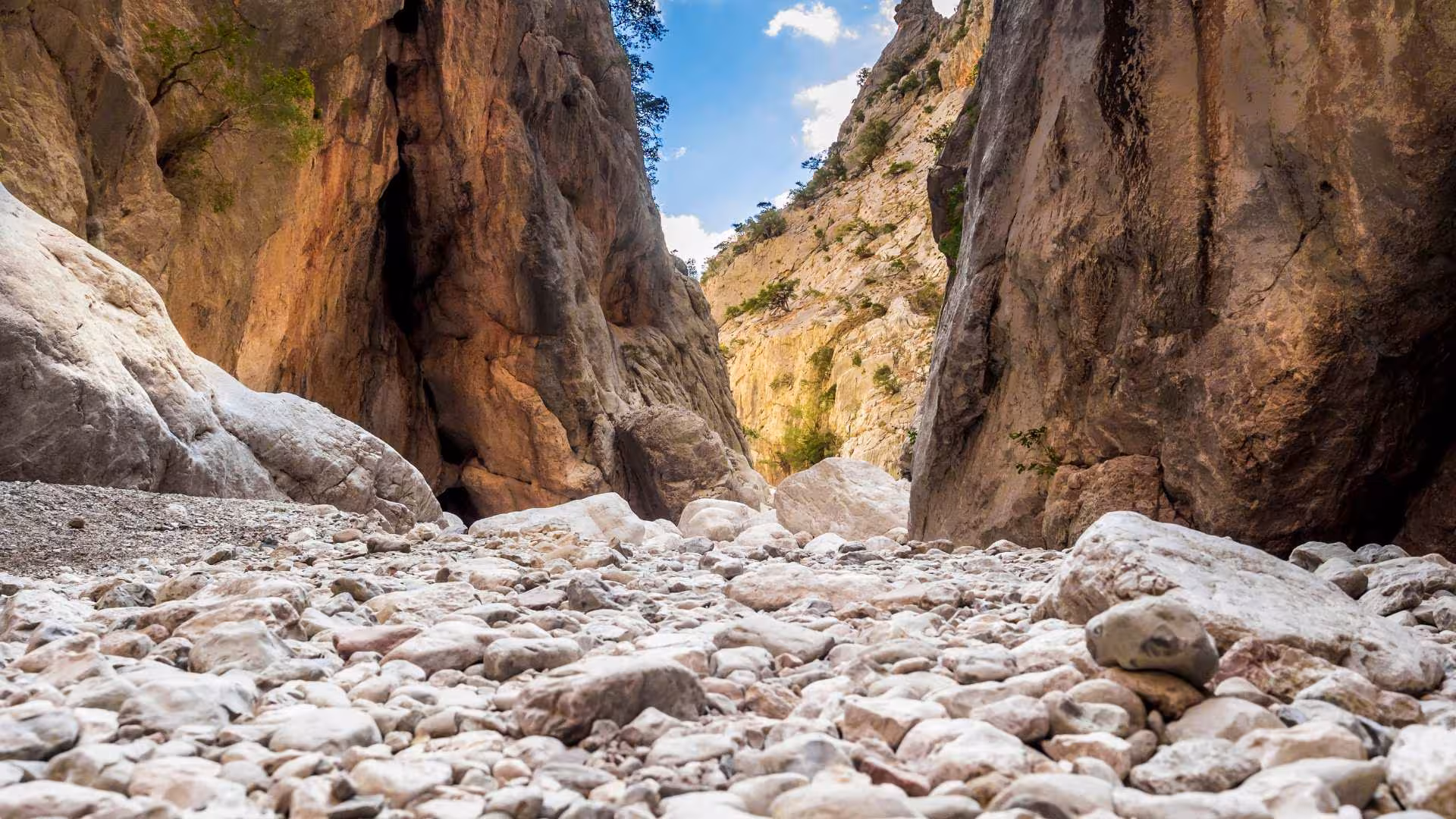 Rocky path leading through narrow passage in Gorropu Canyon, highlighting trekking adventure in Sardinia's scenic landscape.