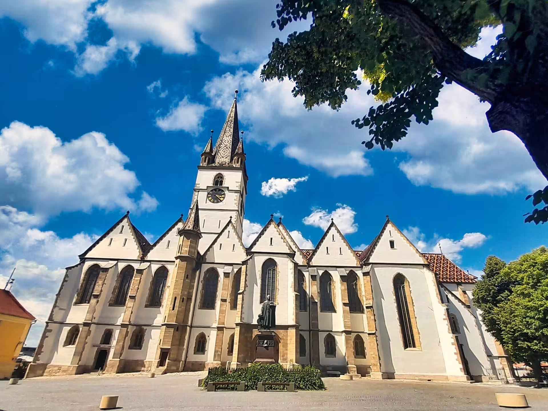 Gothic Lutheran Cathedral of Saint Mary in Sibiu with tall spire under blue sky on Cluj-Napoca day trip