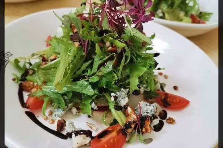 Fresh garden salad with cherry tomatoes, blue cheese, and balsamic drizzle, perfect for a gourmet food tour.