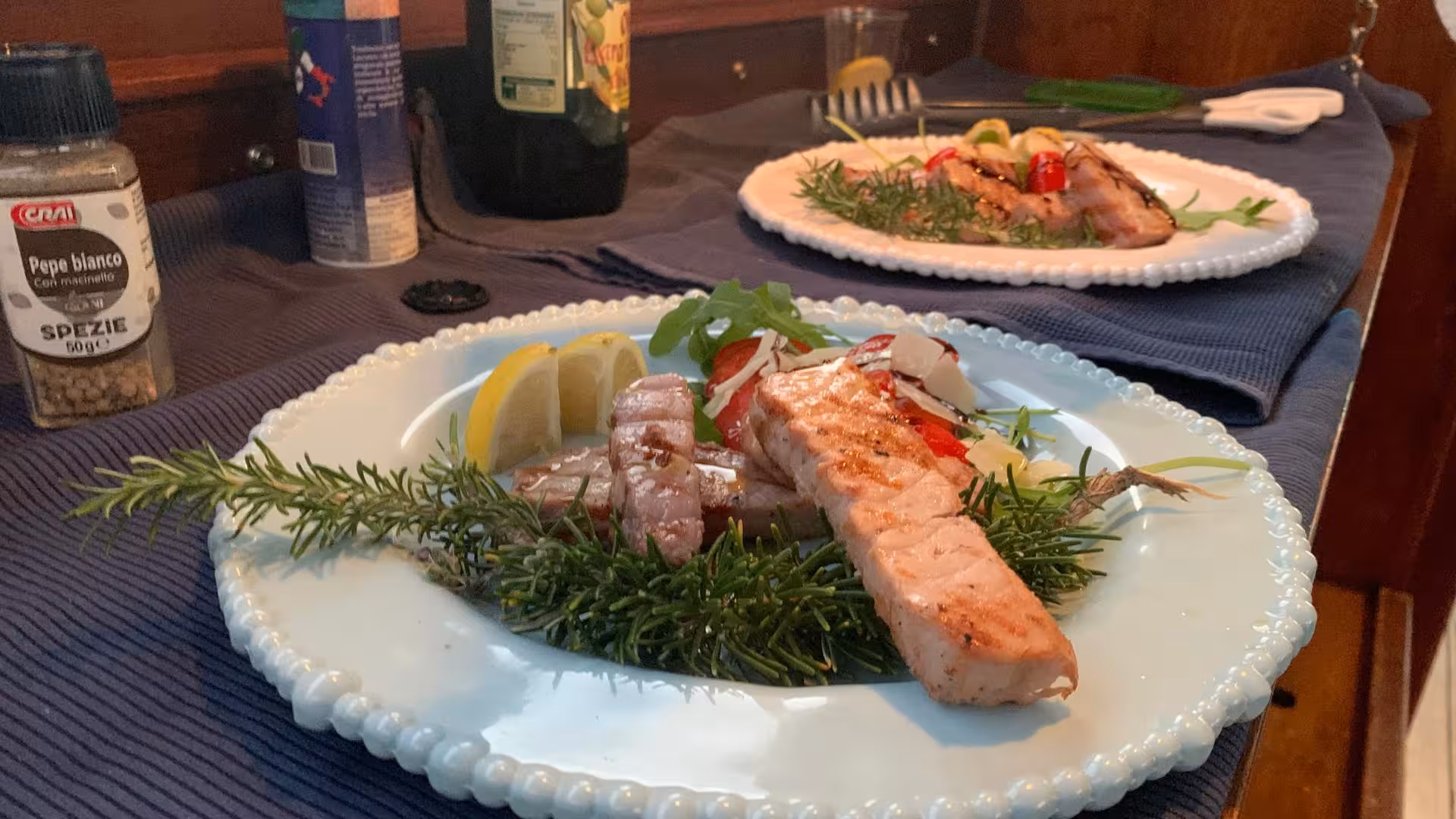 Gourmet seafood dishes elegantly plated with fresh herbs and lemon served on a wooden boat tour in La Maddalena.