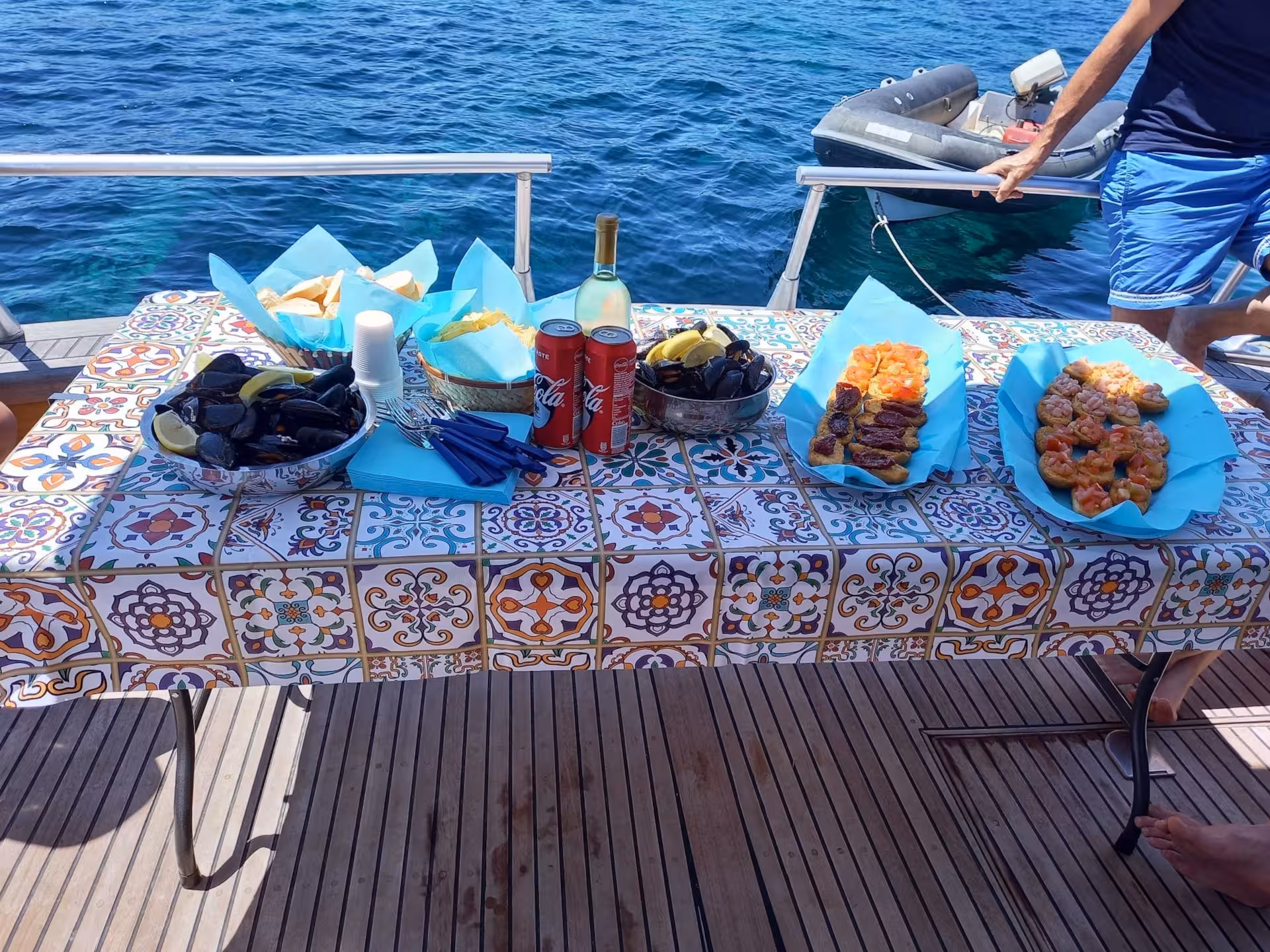 Gourmet seafood spread on a boat with scenic views of La Maddalena Archipelago from Palau tour.